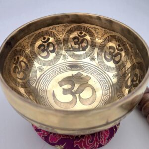 Bol tibétain gravé OM posé sur un coussin, avec motifs OM gravés à l’intérieur