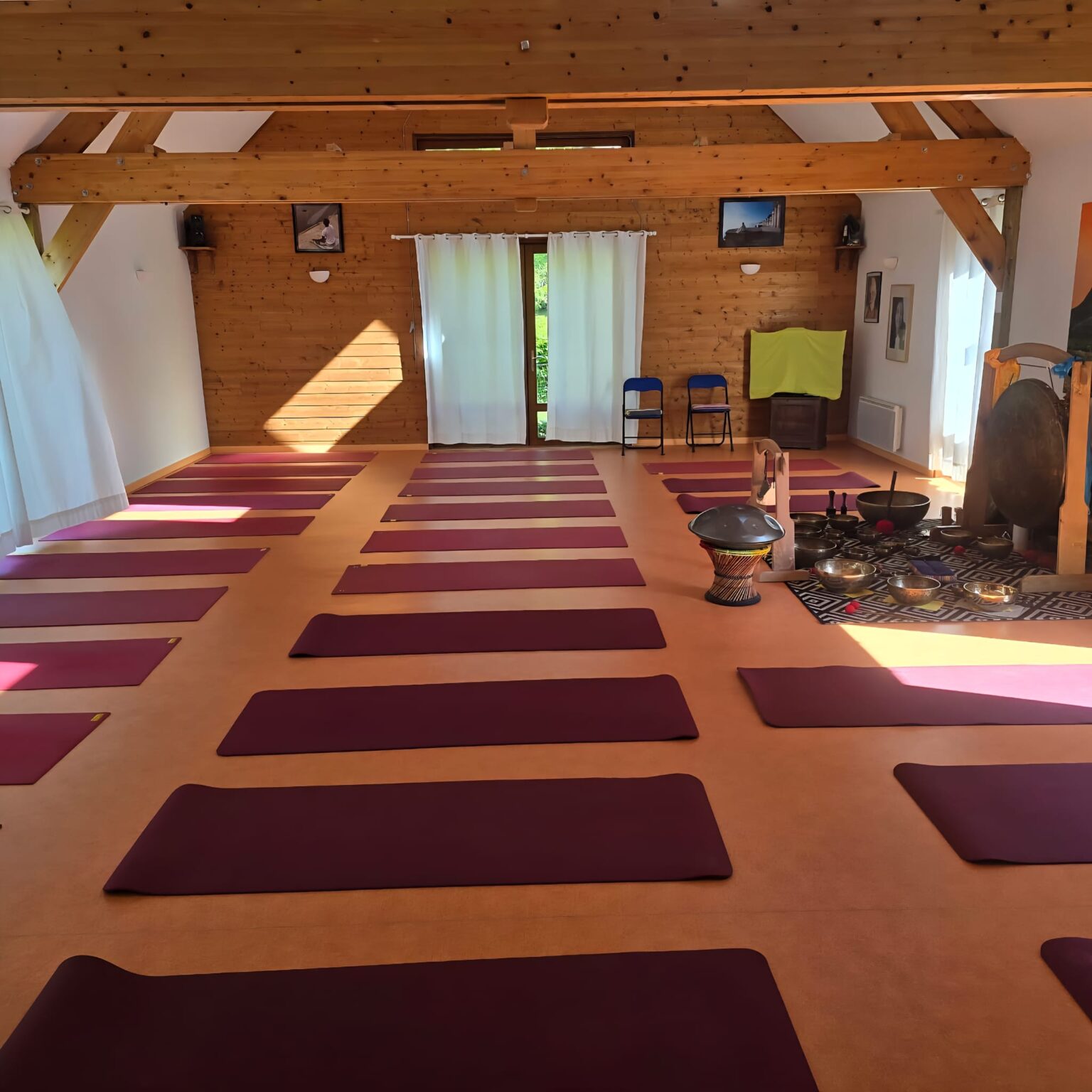 Salle de pratique avec tapis au sol, bols chantants tibétains et gongs disposés pour une séance collective