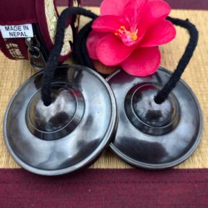 Vue de dessus de tingshas tibétaines en 7 métaux finition noire avec pochette textile zippée du Népal