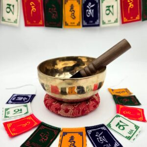 Bol chantant tibétain brut 7 métaux 402 g en Sol♯ – vue extérieure avec bâton bois sur coussin rouge et drapeaux de prière